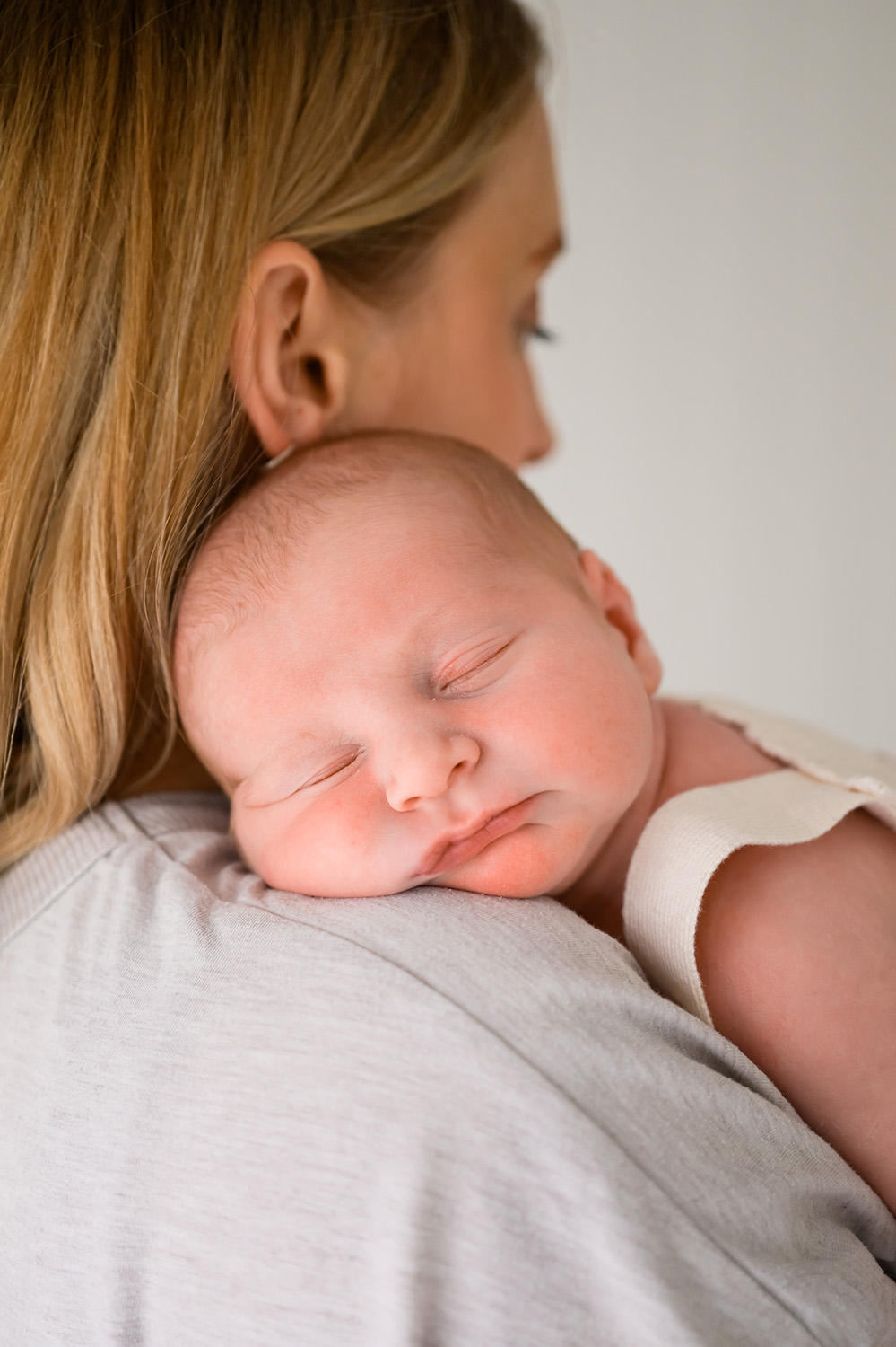sleeping newborn baby resting his head on mums shoulder