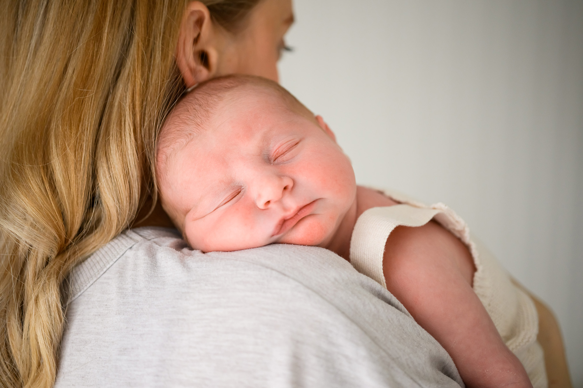 newborn baby sleeping on mums shoulder in studio